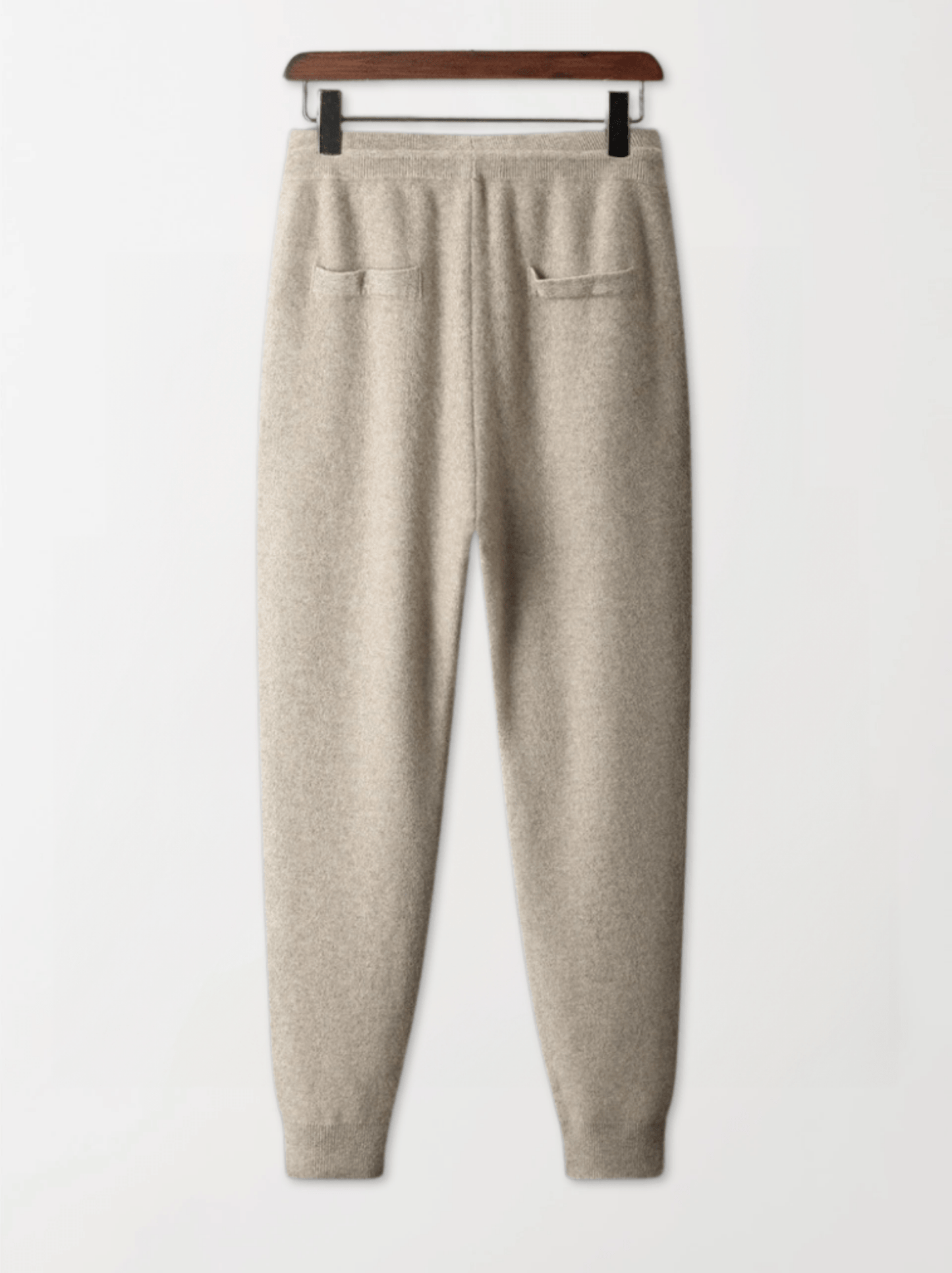 Beige sweatpants on a hanger against a white background