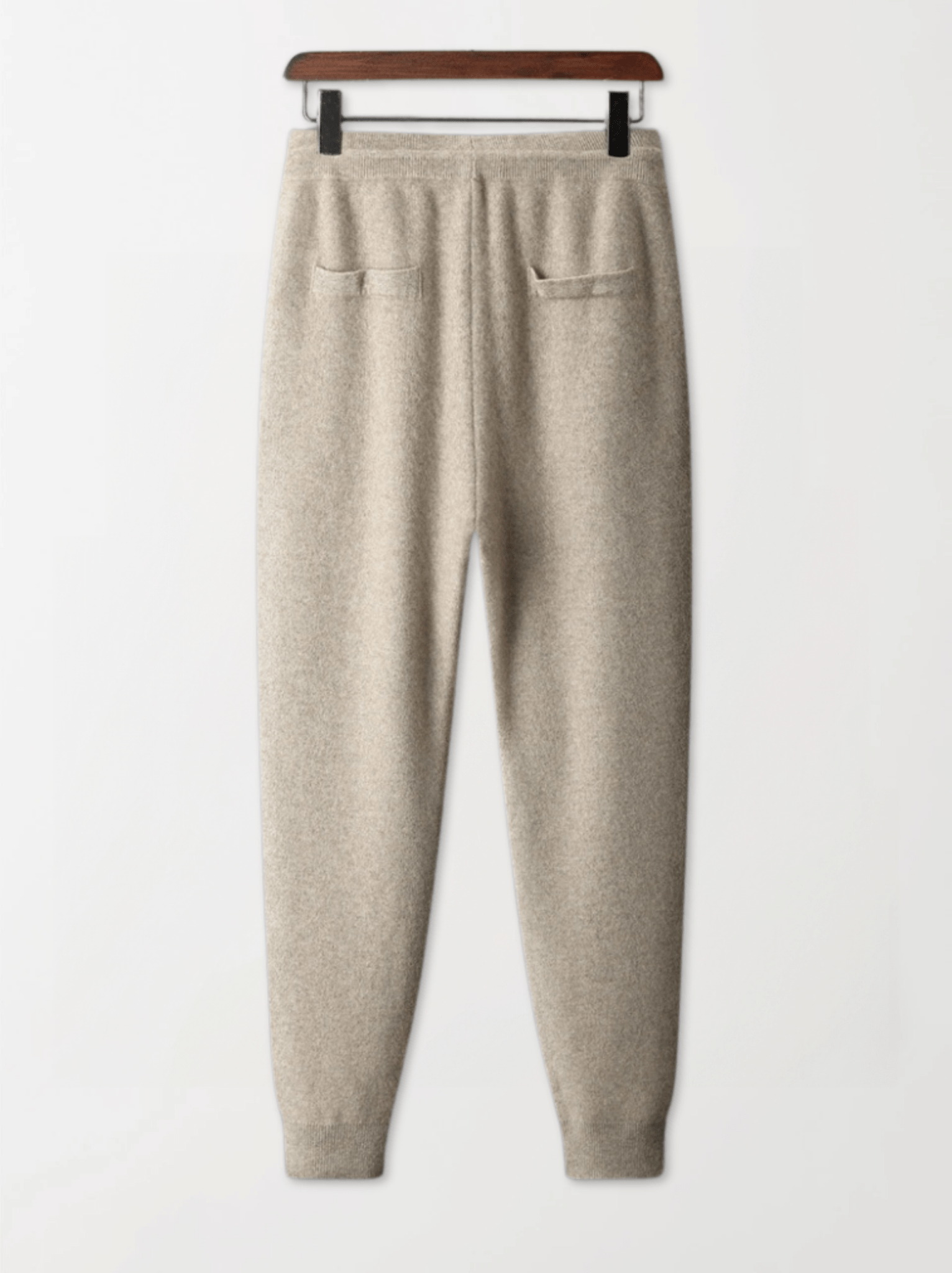 Beige sweatpants on a hanger against a white background