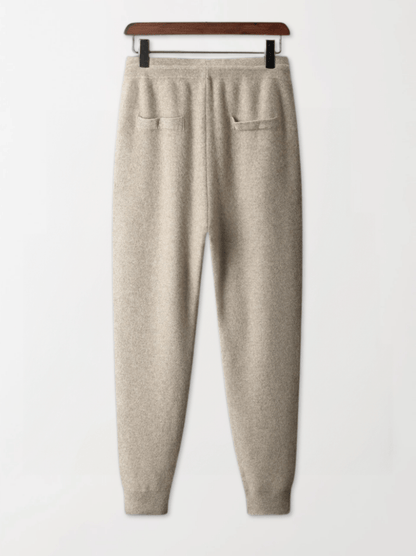Beige sweatpants on a hanger against a white background