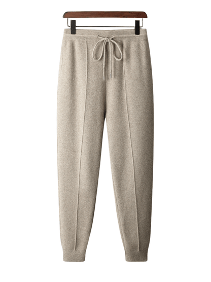 Beige sweatpants on a hanger against a white background
