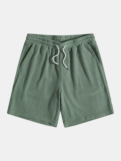 Green shorts with a drawstring on a light gray background