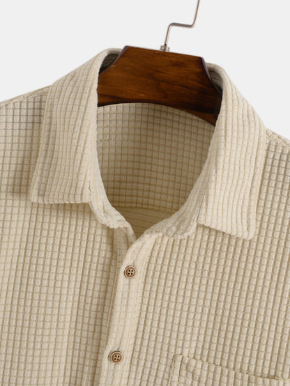 Beige checkered shirt on a wooden hanger against a white background