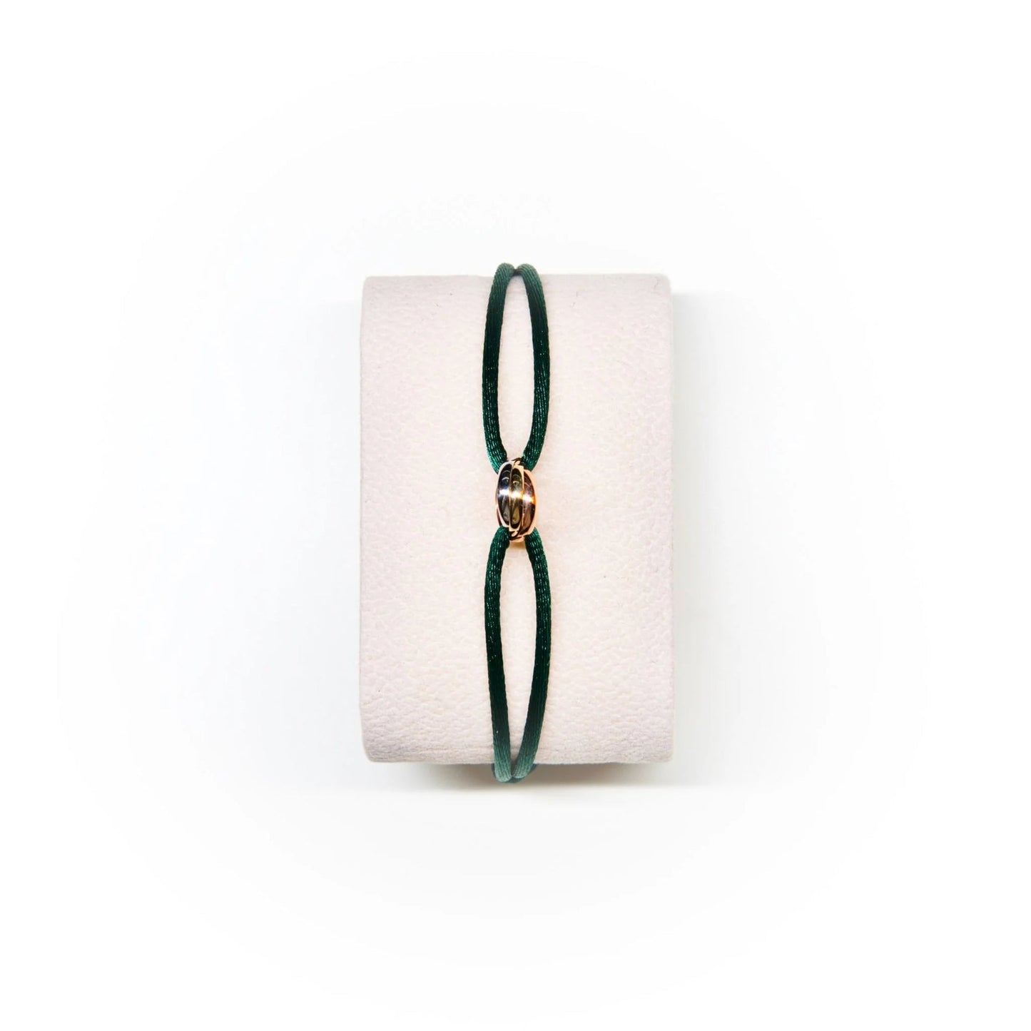 Green bracelet on a white cushion with a white background