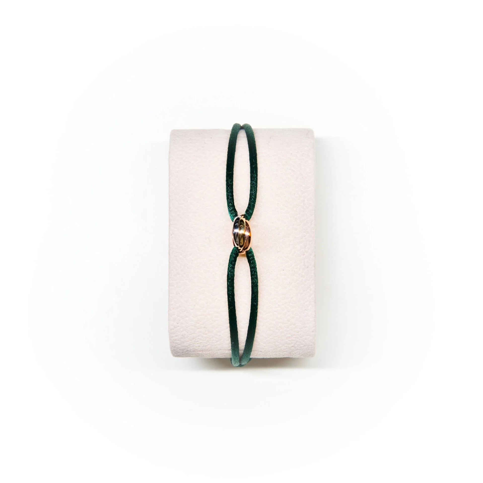 Green bracelet on a white cushion with a white background